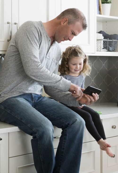 father with daughter using tech